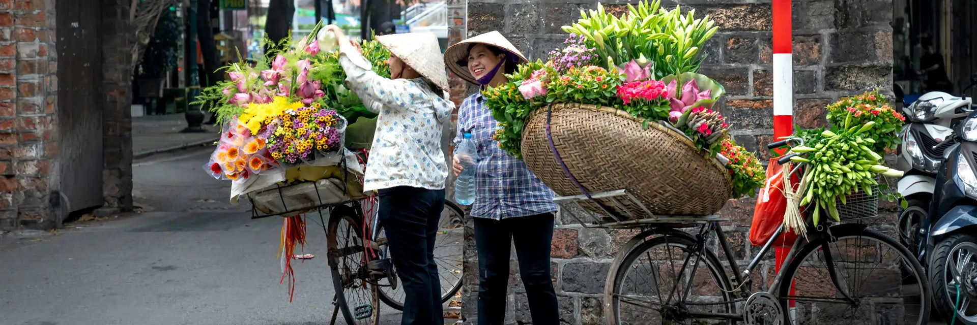 Two Chinese florists with abundant flower baskets on bicycles in an urban setting in China